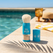 Blue Sol Brush mineral sunscreen brush uncapped at the pool edge with its sun print cap beside it