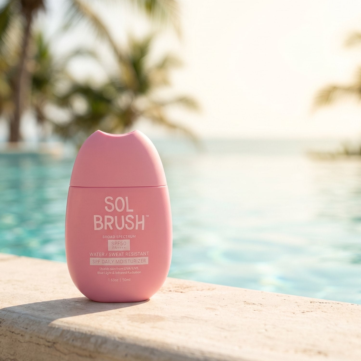 Sol Brush Daily Moisturizer Broad Spectrum SPF 50 on a pool ledge with palm trees and ocean behind