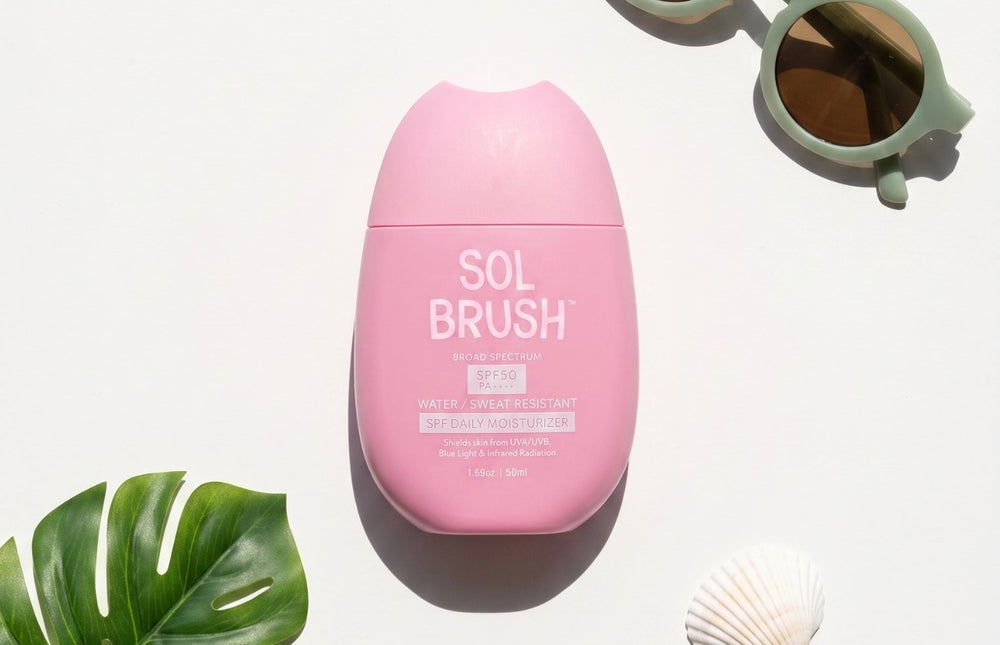 Sol Brush Broad Spectrum SPF 50 Daily Moisturizer bottle with sunglasses and a monstera leaf