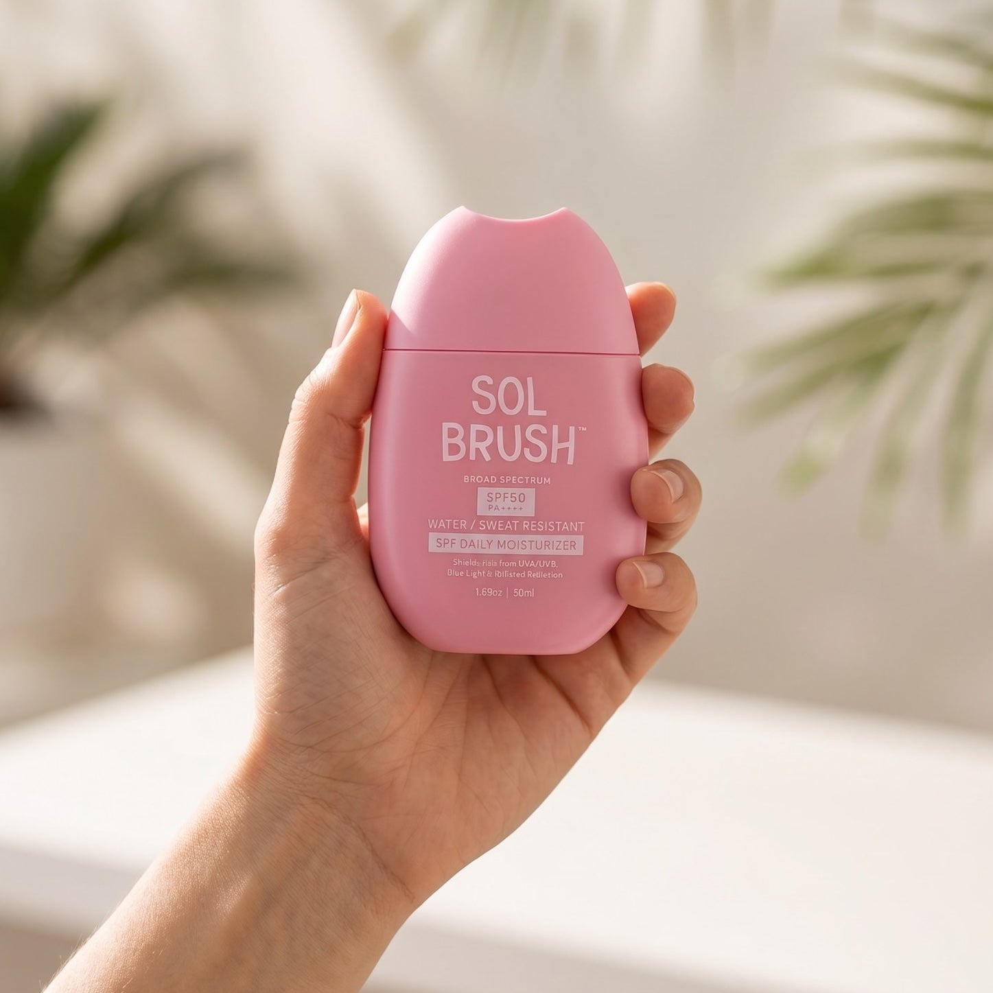 Hand holding the palm size Sol Brush Daily Moisturizer Broad Spectrum SPF 50 bottle